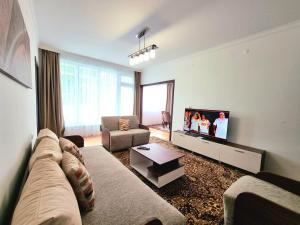 a living room with a couch and a flat screen tv at Comfortable Family Apartment with Parking in Burgas