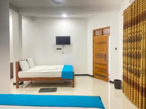 a bedroom with a bed and a tv on the wall at La Maison Yala in Tissamaharama