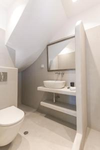 a white bathroom with a sink and a toilet at Alexandros Apartments in Naousa