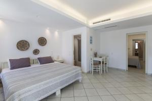 a white bedroom with a large bed and a table at Alexandros Apartments in Naousa