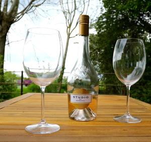 Dois copos de vinho e uma garrafa numa mesa de madeira em The Cabin at the Croft - Idyllic rural retreat perfect for couples and dogs em Leigh