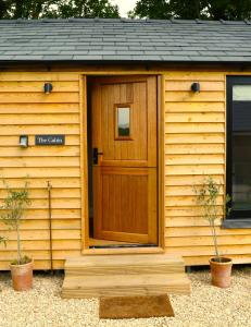 eine Holzhütte mit einer Tür und einem Fenster in der Unterkunft The Cabin at the Croft - Idyllic rural retreat perfect for couples and dogs in Leigh