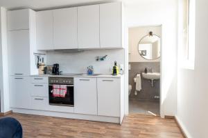 a kitchen with white cabinets and a sink at Penthouse Panoramablick Whirlpool Parken in Koblenz