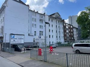 a white building with cars parked in a parking lot at Hotel Horstmann Münster in Münster