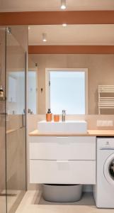 a bathroom with a sink and a washing machine at Apartament RAINBOW SurfingBird Dźwirzyno in Dźwirzyno