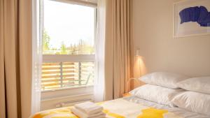 a bedroom with a window and a bed with towels on it at Apartament RAINBOW SurfingBird Dźwirzyno in Dźwirzyno