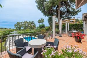 un patio con sillas, una mesa y una piscina en Beachside Villa in Carib Playa en Marbella