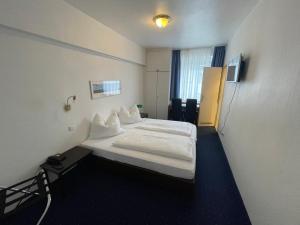 ミュンスターにあるHotel Horstmann Münsterの白いシーツが備わるベッドが備わる小さな客室です。