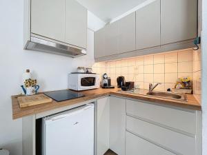 Una cocina con gabinetes blancos y un microondas. en 3348 - appartement à 200m de la plage, en Le Barcarès