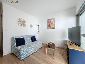 Una sala de estar con un sofá y un televisor de pantalla plana. en 3348 - appartement à 200m de la plage, en Le Barcarès