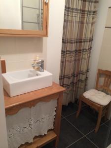 a bathroom with a white sink and a chair at La Cucumelle in La Salle Les Alpes