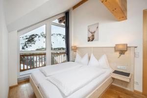 uma grande cama branca num quarto com uma grande janela em Appartement Haus Faßwald em Obertauern