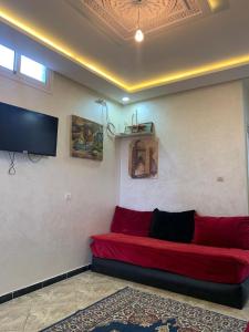 ein rotes Sofa in einem Zimmer mit einem Flachbild-TV in der Unterkunft Dar Soltan Oualidia in Oualidia