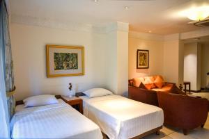 Habitación de hotel con 2 camas y sofá en The Patra Bali Resort & Villas - CHSE Certified en Kuta