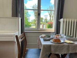 une table avec une assiette de nourriture et une fenêtre dans l'établissement Villa du Vieux Château, aux Andelys