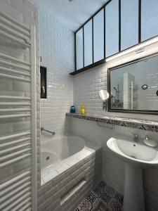 La salle de bains blanche est pourvue d'une baignoire et d'un lavabo. dans l'établissement Villa du Vieux Château, aux Andelys