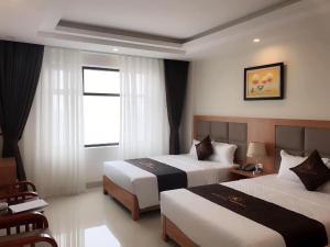 a hotel room with two beds and a window at Royal Hotel Sầm Sơn in Sầm Sơn