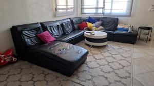 un sofá de cuero negro en una sala de estar con mesa en BM PAVILLONS, en Goussainville 1 foto más
