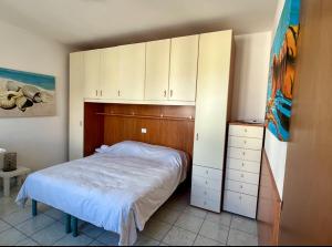 um pequeno quarto com uma cama e armários brancos em AppArt 24 city center parking and Sea em Lignano Sabbiadoro