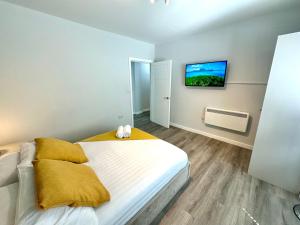 a bedroom with a bed with a tv on the wall at Spacious One Bedroom Apartment - With Parking and WiFi - Town Centre Location - Gated Access - Walk to Beach! in Bournemouth
