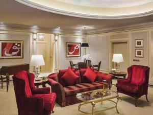 a living room with a red couch and two chairs at Mövenpick Hotel Al Khobar in Al Khobar