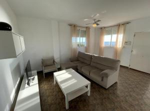 ein Wohnzimmer mit einem Sofa und einem Tisch in der Unterkunft Apartamentos Cap y Corp in Alcossebre