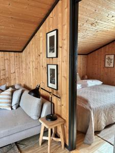 1 dormitorio con 1 cama en una pared de madera en Hytte nær Ål, 