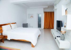 ein weißes Schlafzimmer mit einem großen Bett und einem TV in der Unterkunft HOTEL CONTINENTAL in Abidjan