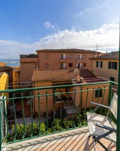 einen Balkon mit einem Stuhl und einige Gebäude in der Unterkunft EasyTopStay - Porto Ercole Cosy Flat in Porto Ercole
