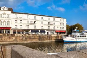 un barco en el agua frente a un edificio en Best Western Le Cheval Blanc -Vue sur le port-plein centre ville, en Honfleur