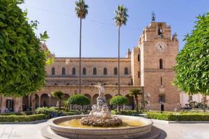 a fountain in front of a building with a clock tower at Carmine House in Monreale