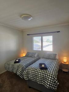 2 camas en un dormitorio con 2 lámparas y una ventana en Premium 3 bedroom River Front Location, en Rockhampton
