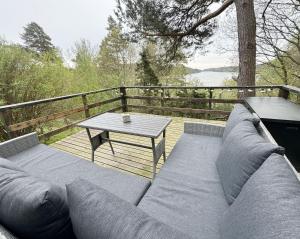 um sofá e uma mesa num deque de madeira em Cozy cottage in a beautiful setting by the Abyfjorden-Brastad em Brastad