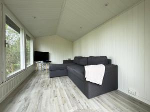 uma sala de estar com um sofá e uma televisão em Cozy cottage in a beautiful setting by the Abyfjorden-Brastad em Brastad