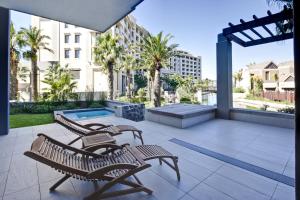 un patio con 2 sillas y una piscina en un edificio en Lawhill Luxury Apartments - V & A Waterfront, en Ciudad del Cabo