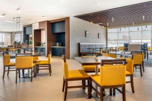 a dining room with yellow chairs and tables at Cambria Hotel Bloomington Mall of America Minneapolis Airport in Bloomington