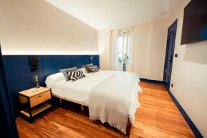 um quarto com uma grande cama branca e piso em madeira em GETXO ROOMS em Getxo