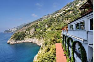 a train on the side of a mountain next to the ocean at Albergo La Conca Azzurra in Conca dei Marini