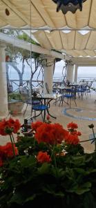 a patio with tables and chairs and red flowers at Albergo La Conca Azzurra in Conca dei Marini