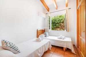 a bedroom with two beds and a window at Villa CASSIA in Cala'n Porter