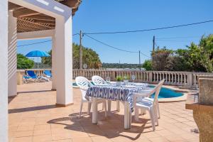 a table and chairs on a patio with a pool at Villa CASSIA in Cala en Porter