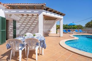 a villa with a pool and a table and chairs at Villa CASSIA in Cala en Porter