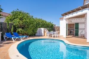 a swimming pool with two blue chairs and a table at Villa CASSIA in Cala en Porter