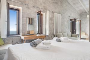 una camera bianca con 2 letti e uno specchio di Milos Paradise Luxury Villas a Ayios Nikitas