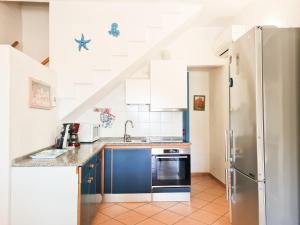La cuisine est équipée de placards bleus et d'un réfrigérateur. dans l'établissement Villetta con vista mare a 80metri dalla spiaggia, à Geremèas