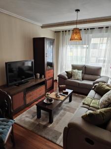 Una sala de estar con dos sofás y un televisor de pantalla plana. en Apto alquiler verano Cangas del Morrazo, en Cangas de Morrazo