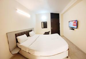 a bedroom with a white bed and a tv at Hotel Red - Vasant Kunj in New Delhi