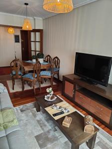 Una sala de estar con una mesa y un televisor. en Apto alquiler verano Cangas del Morrazo, en Cangas de Morrazo