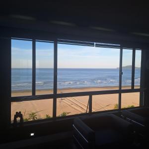 a room with a view of the beach from a window at Oceanview Santos Gonzaga in Santos