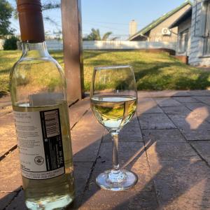 una botella de vino blanco junto a una copa de vino en Vintage on Eden, en Edenvale